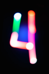 Digit 4. Four. Glowing numbers on dark background. Abstract light painting at night. Creative artistic colorful bokeh. New Year. Use it for build you own design for book cover, poster or post card.