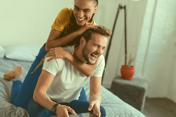 Never bored together. Adorable couple grinning broadly while having fun and joking during their...
