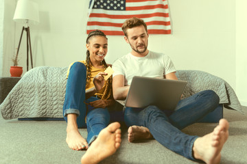 Easy and fast shopping. Relaxed young people sitting on the floor and paying with a credit card while making online shopping at home.