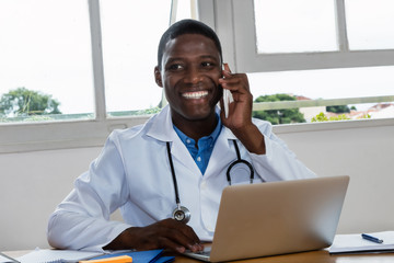 Laughing african american doctor listening to patient at phone