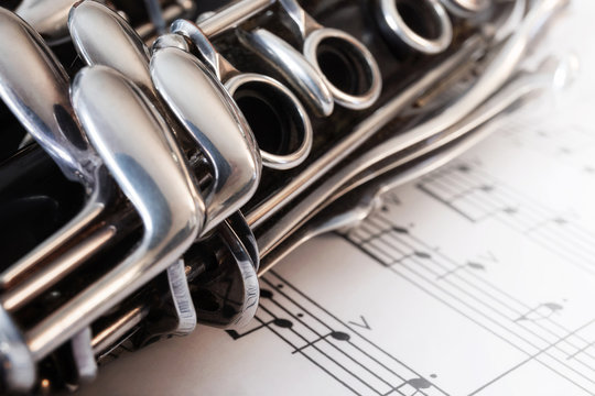 Clarinet, wind musical instrument. Detail with musical score. Clarinet, keyboard in the foreground. The instrument is placed on a musical score with some notes.