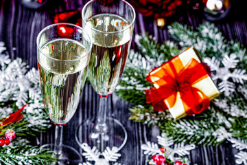 glasses of champagne and Christmas ornaments on dark wooden back