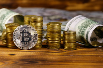 Silver bitcoin and dollars on wooden background