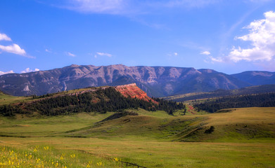 Rolling green hills and mountains along Chief Joseph scenic route in a summertime Wyoming landscape