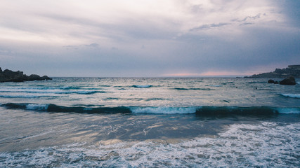 Evening mediterranean sea with waves and foam hitting the shore. Sunset. Malta