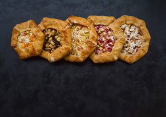 Pattern of different handmade pies on a black kitchen table.
