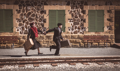 Young couple with vintage suitcase on the trainlines ready for a journey.