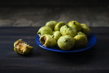 Green figs fruits on blue dish, bitten fruit