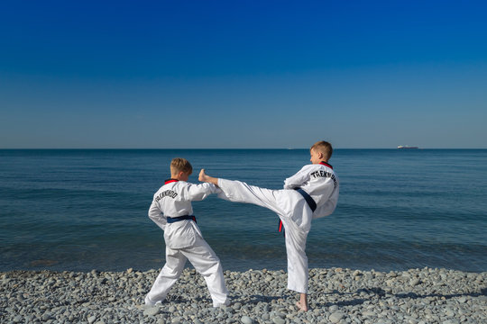 Обучение двух детей на пляже, на море: тхэквондо, спорт