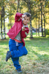 Fototapeta premium Impulsive Caucasian boy yelling and posing in park at autumn, full length portrait