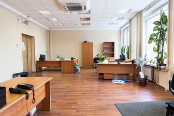 Empty office space with desks, cabinets and flowers after moving, nobody