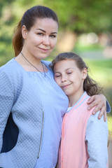 Fototapeta premium Mother with her young daughter stand embracing, girl with closed eyes