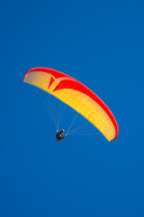 Beautiful yellow and red paraglider flying in colorful sky