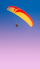 Beautiful yellow and red paraglider flying in colorful sky