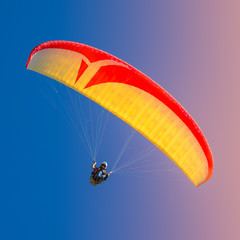 Beautiful yellow and red paraglider flying in colorful sky