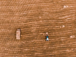 Aerial view drone of harvest field with tractor moving hay bale