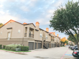 Typical apartment complex condos with attached garage and uncovered parking lots at suburban area in Irving, Texas, USA.