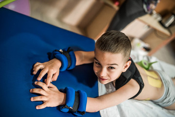 cute kid is going to have physical musculoskeletal therapy in rehabilitation center. Boy look at camera