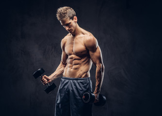 Fototapeta na wymiar Handsome shirtless man with stylish hair and muscular ectomorph body doing the exercises with dumbbells.