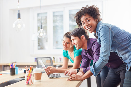 Lachende Studentin mit Kollegen am Laptop