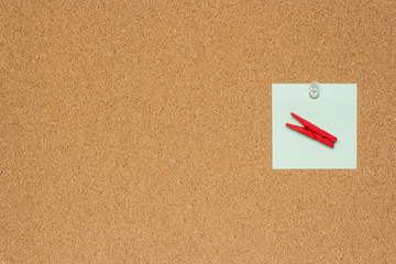 One colorful notes with white pushpins and clothespins isolated on a cork background