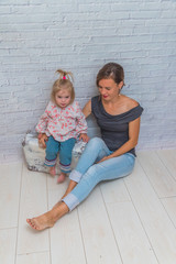 a mother with baby near a suitcase against a brick wall, the girl is sad she was going