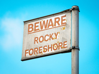Fototapeta premium Beware Rocky Foreshore warning sign on Quayside