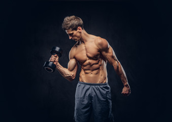 Fototapeta na wymiar Handsome shirtless man with stylish hair and muscular ectomorph body doing the exercises with dumbbells.