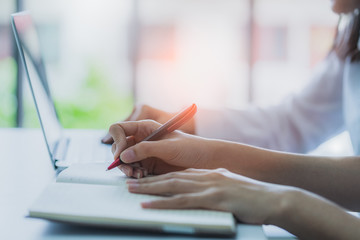 business working with hand type laptop and notebook with background of light from window