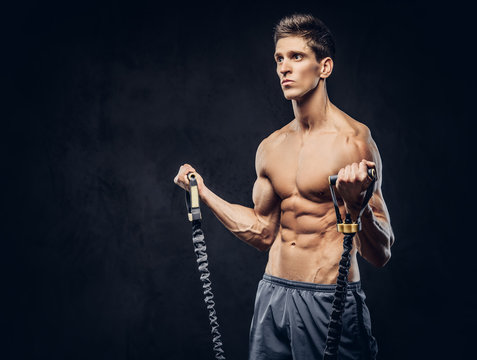 Handsome shirtless man with stylish hair and muscular ectomorph doing the exercises with an expander.