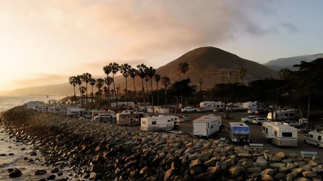 RV park (campground) at coast, California. Ocean. California during sunset. Aerial view, from above, drone flying over water.
