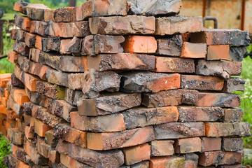Defective red clay bricks are stacked on wooden pallets. Waste production of bricks from clay. Copy space