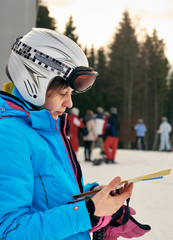 Portrait of young female skier holding ski track map