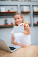 Woman holding a credit card. Focus on the foreground.