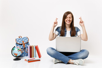 Young woman student hold laptop wait for special moment keep fingers crossed and eyes closed near globe backpack school books isolated on white background. Education in high school university college.