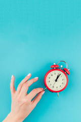 Woman hand holding the red vintage alarm clock