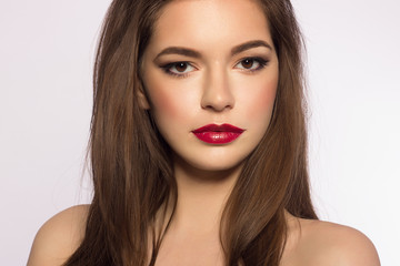 Close up portrait of a beautiful young female face with red lips and long brown hair. Classic make...