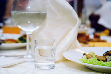 A glass glass with vodka on a serving table. Close-up.