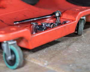 Auto repair shop tools on a creeper in a garage