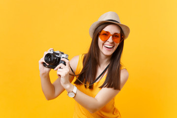 Tourist woman in summer casual clothes, hat take picture on retro vintage photo camera isolated on yellow background. Girl traveling abroad to travel on weekends getaway. Air flight journey concept.