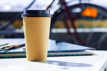 Disposable coffee cup on the rough art studio table. Arty colorful and creative mood. 