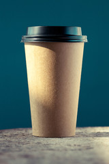 Disposable coffee cup on the rough art studio table. Arty colorful and creative mood. 