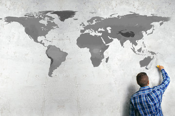A man draws a world map on the wall. Geopolitics concept.