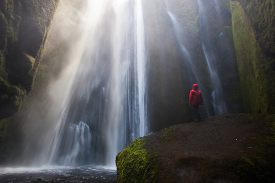 Hombre con abrigo rojo en la cascada oculta Gljufrafossl en Islandia