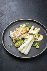 Modern German fried cod fish filet with white asparagus in hollandaise sauce with roast potatoes...