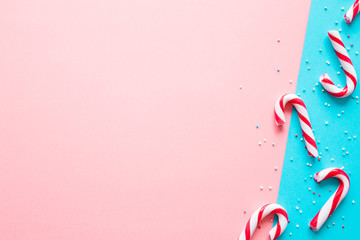 Red and white candy canes on pastel pink and turquoise blue tone paper background. Greeting card. Mockup for positive idea. Empty place for happy, funny cheerful text, quote or sayings.