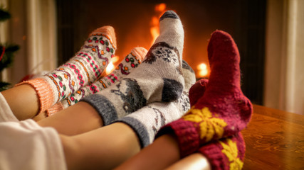 Image of family warming their feet at burning fireplace at living room