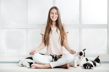 Young beautiful girl hugging a many puppies of a French bulldog