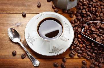 Traditional espresso cup with mocha, coffee beans and scoop on wood background. Top view