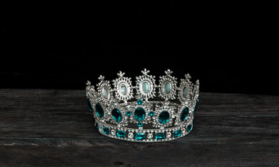 silver royal crown on a black wooden background
